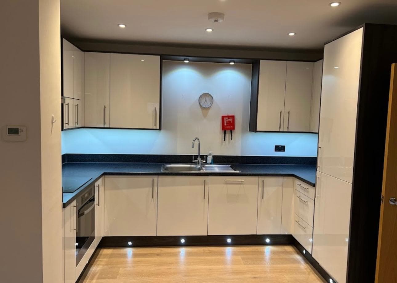 Kitchen with gloss units, dark worktops and a wood floor after a clean by Berkshire EcoClean